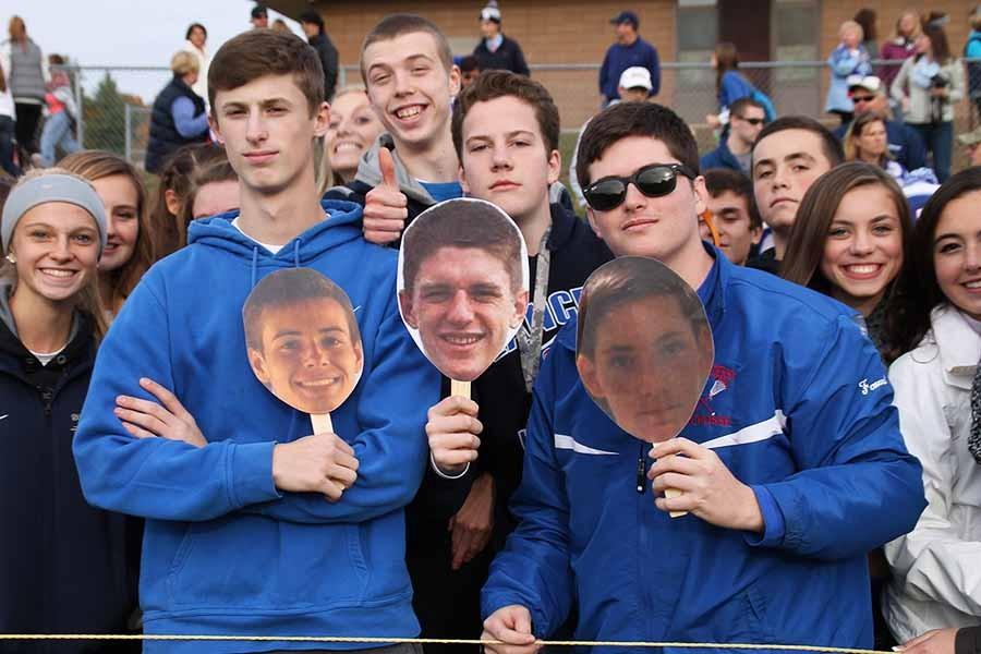 Fans on the sideline support their favorite teamembers with heads on sticks.