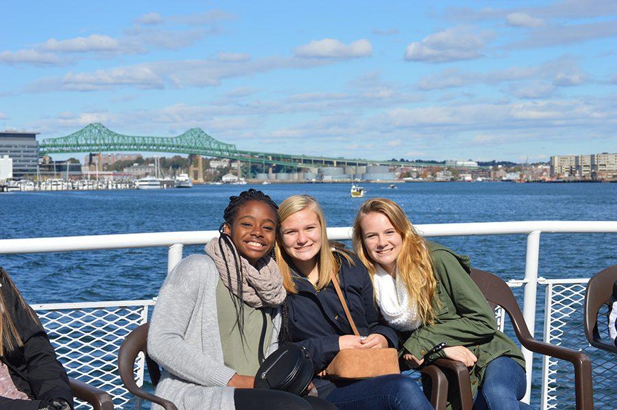 Junior AP Gov students Kiara Breault, Kalin Gregoire, and Ally Rose relax on the upper deck of The Rita with the views of the harbor behind them and Boston before them.