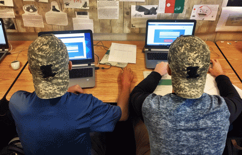 Juniors Joe Wanders and Owen Stowell sport Operation Hat Trick hats while doing their work in English teacher and ALC adviser Mrs. Rich's class.