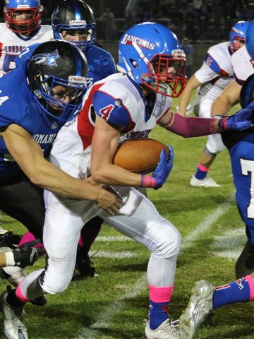 Merrimack defenseman reaches to try and tackle Holland as he holds onto the ball, running and warding off defenders.
