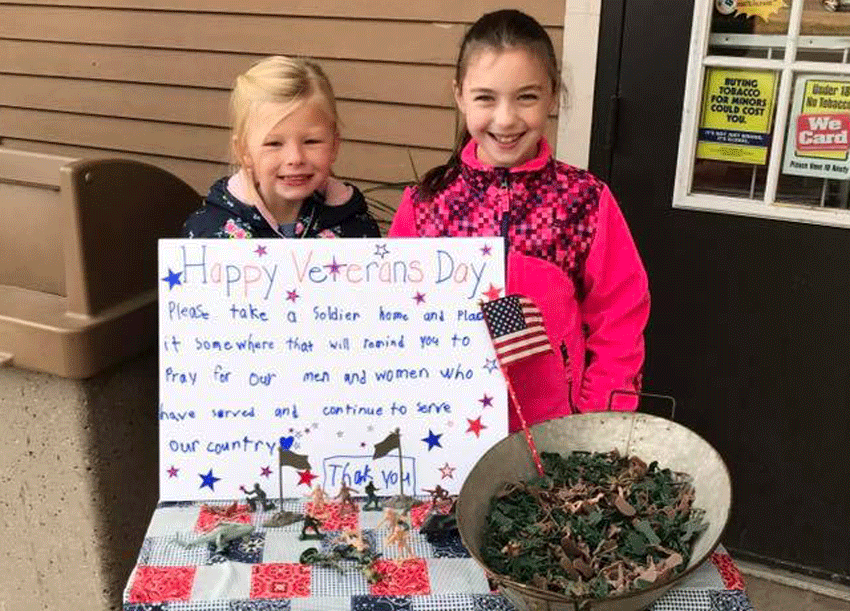 Grace Rich, a 3rd grader at South School, and her friend Emily Hoyt, a 3rd grader at Matthew Thornton, pass out toy soldiers in front of the Nutfield store in Londonderry on Veterans Day.  