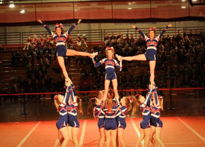 The cheerleaders perform their ending posture in the pyramid. 