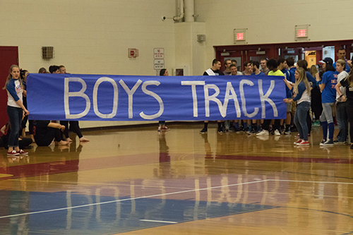 Boys indoor track runs out to a gym full of students at the winter pep rally.