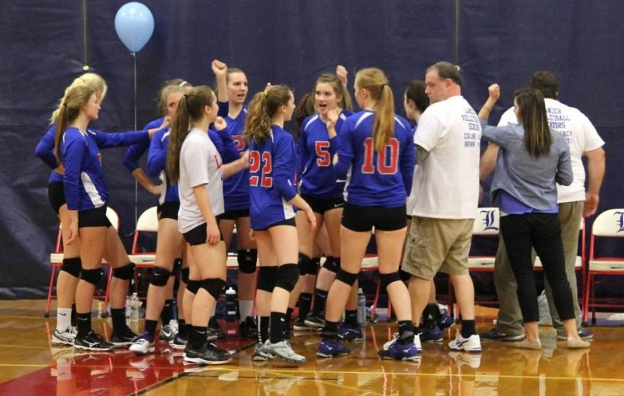 Girls volleyball huddles together after a successful match.