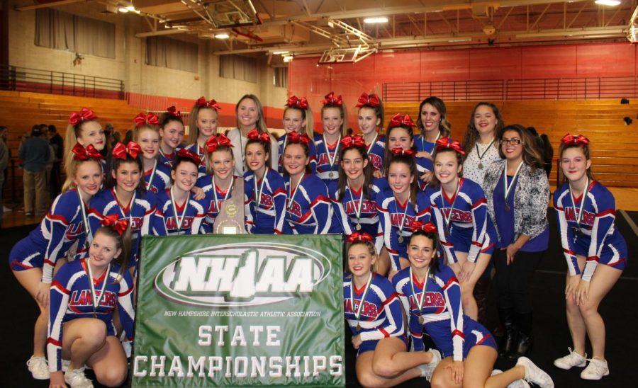 The entire varsity cheer team squeezes in for a photo beside their State Championships banner and new plaque to take back home.