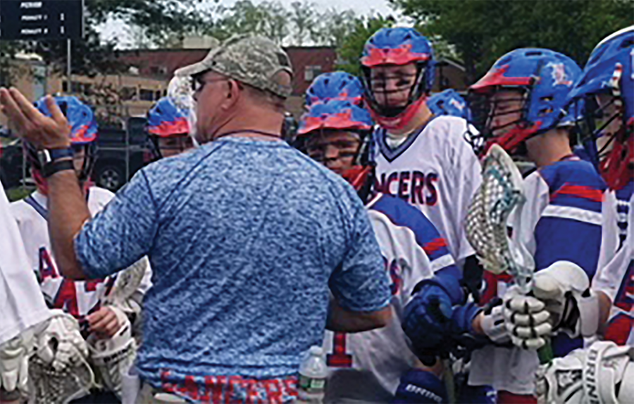 The boys lacrosse team surrounds Coach Sampson prior to their game as he explains various tactics for them to use.