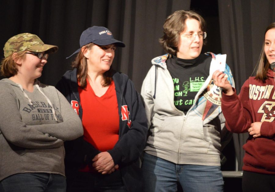 Senior Abby Knights, Mrs. Kern, Mrs. Juster and Junior Celia Ponto explain the card game on the stage at the Teacher Talent Show. 