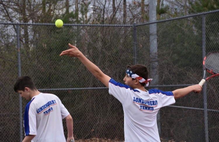 Ness prepares to serve in a doubles match while sporting his American flag headband.