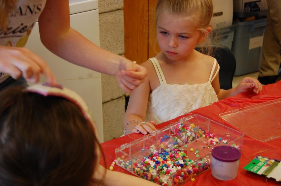 Ainsley watches as she gets taught how to make the perfect bracelet. Her favorite part of the day was dressing up pretty.