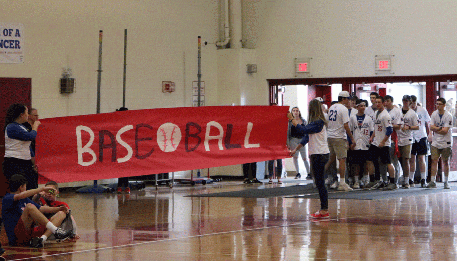 The varsity baseball team waits for Mr. Juster to call on them, so they can tear through their sign at the recent spring pep rally.