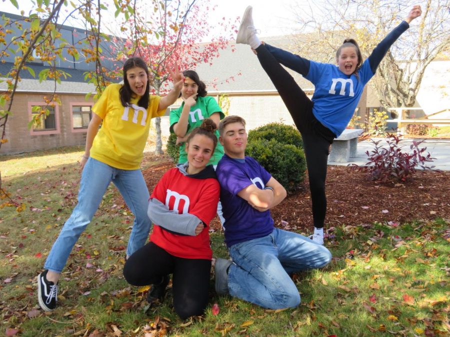 McCutcheon (yellow), Morani (green), sophomore Laura Haas (blue), senior Kait Bedell (red), and Cavanaugh (purple) get into the wacky spirit of their collaborated costumes. Each of their shirts cost $3 to produce, making the combined total for the entire ensemble $15.