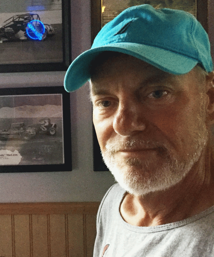 My Dad smiles at a restaurant in Maine next to a picture of his own father, who was a race car driver.
