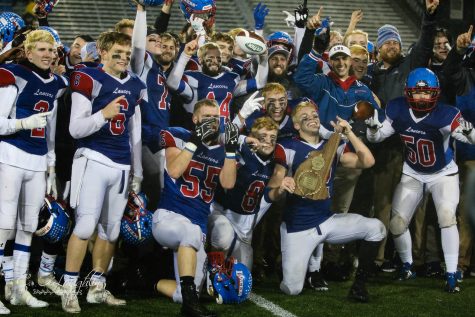 Senior running back Jeffery Wiedenfeld holds the championship plaque while his teammates celebrate with him. The Lancers won the Division One State Championship game 21-10 over Exeter.