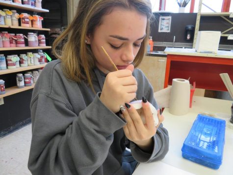 Senior Taylor Hand paints her clay project. 