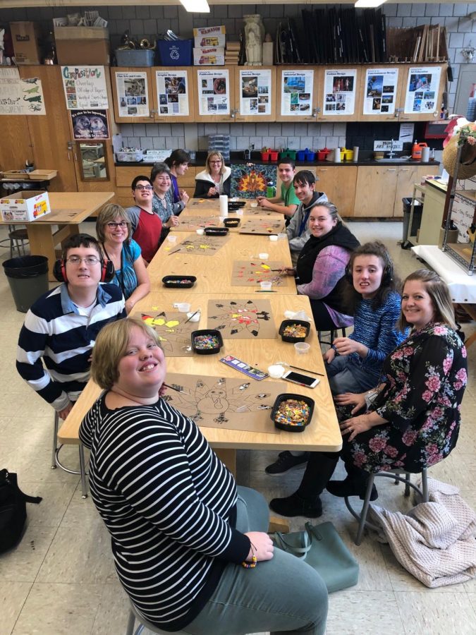 The art interactive class takes a quick break from working on their mosaic turkey art projects. Members of this class work with helpers as they learn how to create a variety of pieces of art.