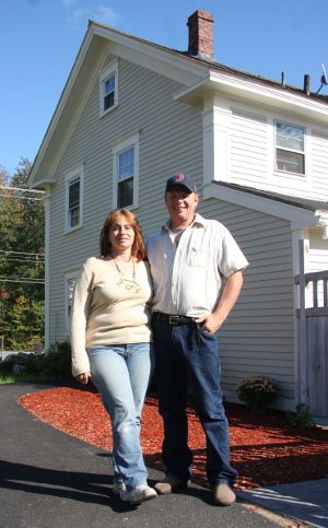 Paul and her husband pose in front of their office. This photos taken on the 15 year anniversary of the paper.