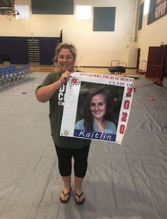 House 4 Assistant Principal Ms. Sullivan poses with a graduating seniors banner that was coordinated by the Rotary Club and hung on Mammoth Road. 