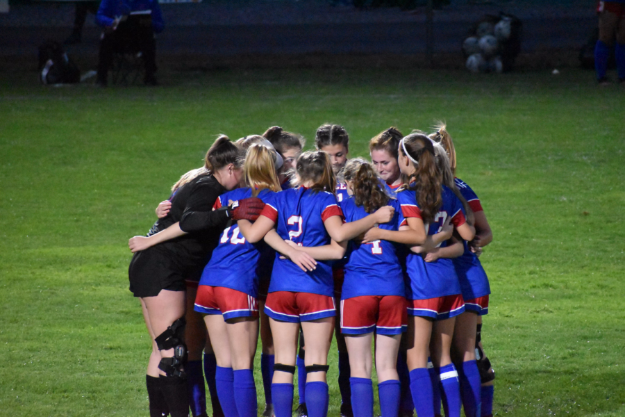 Girls soccer huddles together before the Mack Plaque game.