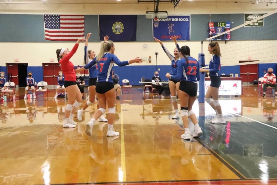 The volleyball team throws their hands up after winning a point. 