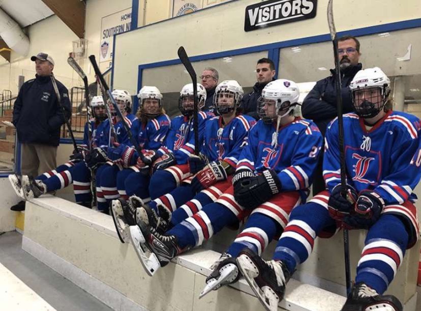 Lancer Varsity Hockey players rest on the side while cheering for their team.This was one of many Friday night games that led them to have a successful season. 