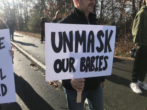 Protestors carry signs to show their disapproval of the mask mandate.