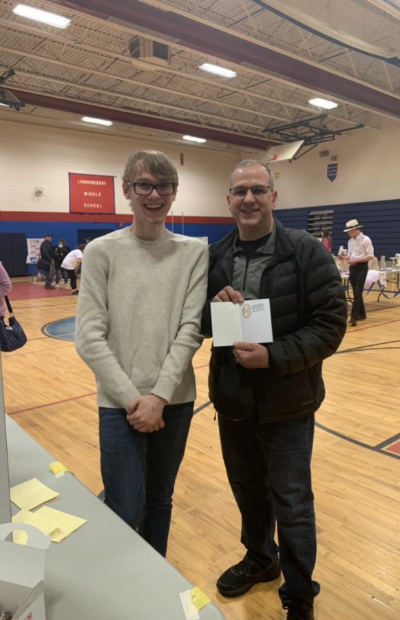 International Club volunteer Michael Pitts adds a sticker to LHS Physics teacher Anthony Cariellos passport after visiting the Italian setup. 