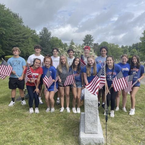 Members of the Pay it Forward club crowd around flags at a cemetery for Memorial Day 2022. The club volunteered time to set flags up around the graves in honor of the soldiers at cemeteries around town. (Photo used with permission from Katie Sullivan)
