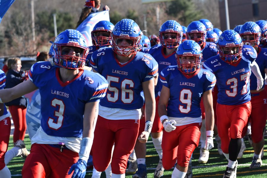 #3 senior Trevor Weinmann leads his team holding their iconic flag to make their entrance on the field.