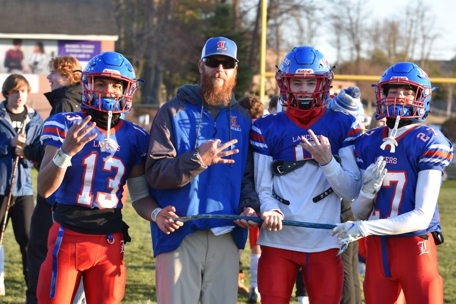 Left to Right: #13 junior Cam Brutus, Coach Sam Carey, #6 senior Kyle McPhail, #27 junior Seth Doyon gather together.