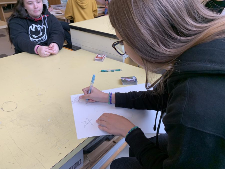 Sophomore Elana Kenney adds to the group drawing since she lost in the first round of blackjack, which art club plays for fun.