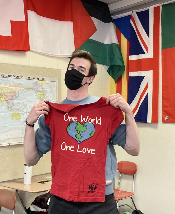 President Sean OMara holds a shirt that reads One World, One Love. This photo was taken last year during a clothes sort in preparation for the first ever Thrift Fair.