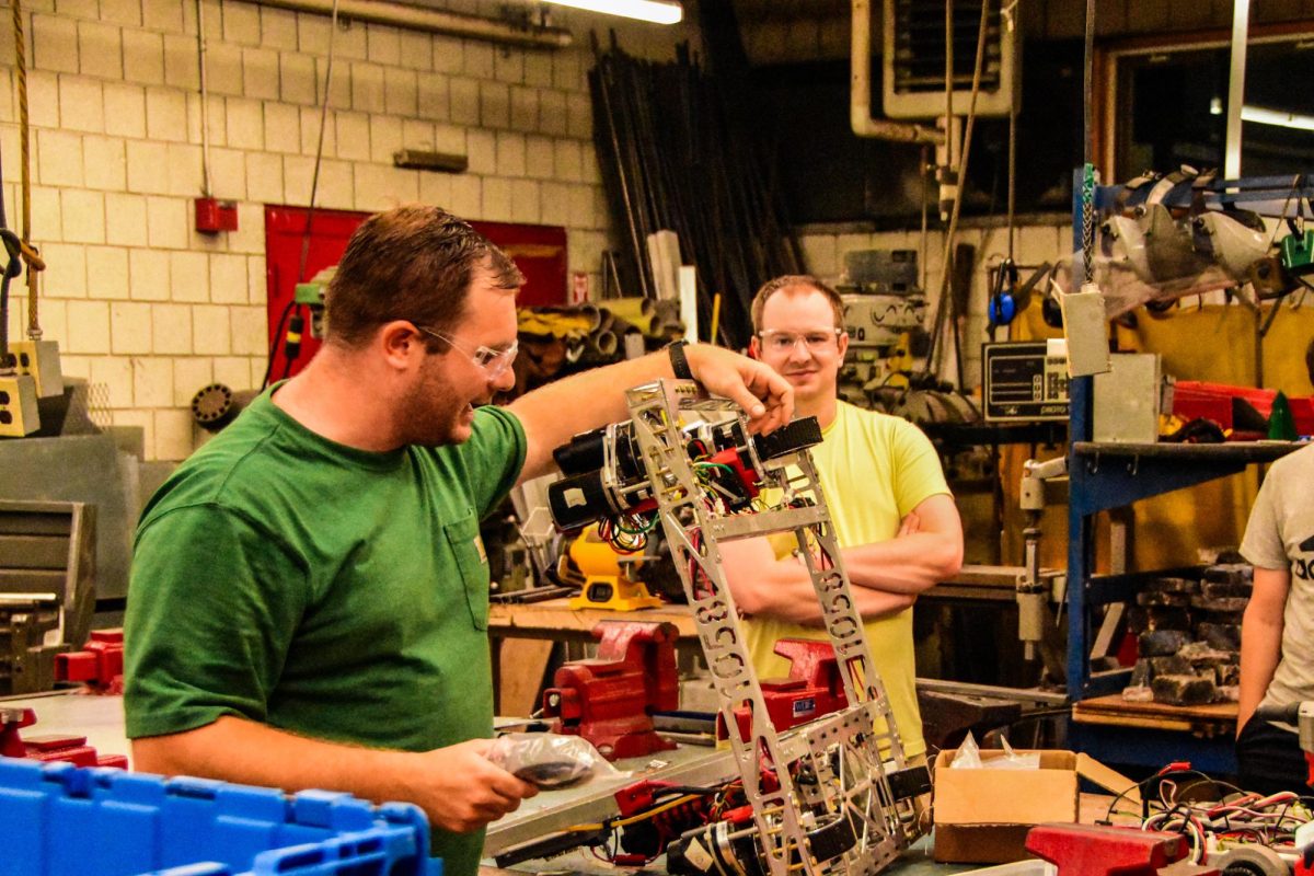 Robotics mentor Brendon McLeod shows off the new swerve module drivetrain that the team has been developing.