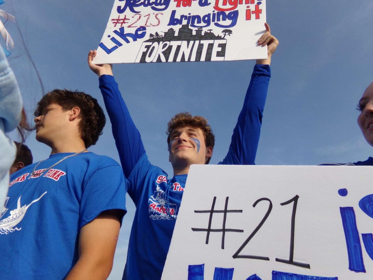 Senior Brandon Morin supports the team and holds a sign for number 21, junior Evan Fortin. 