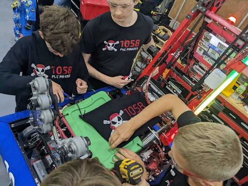 Sophomore Ben Simpson and senior Brandon Adamson attach a shield above the robot’s internals during the Governor’s Cup qualifying matches.	