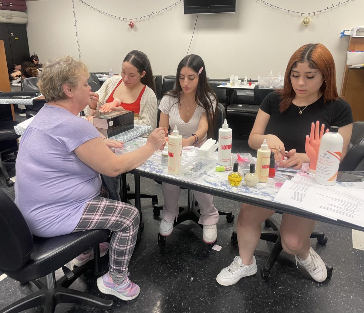 Mollie Chase helps a group of her students prepare for the maicure portion of their state board exams.