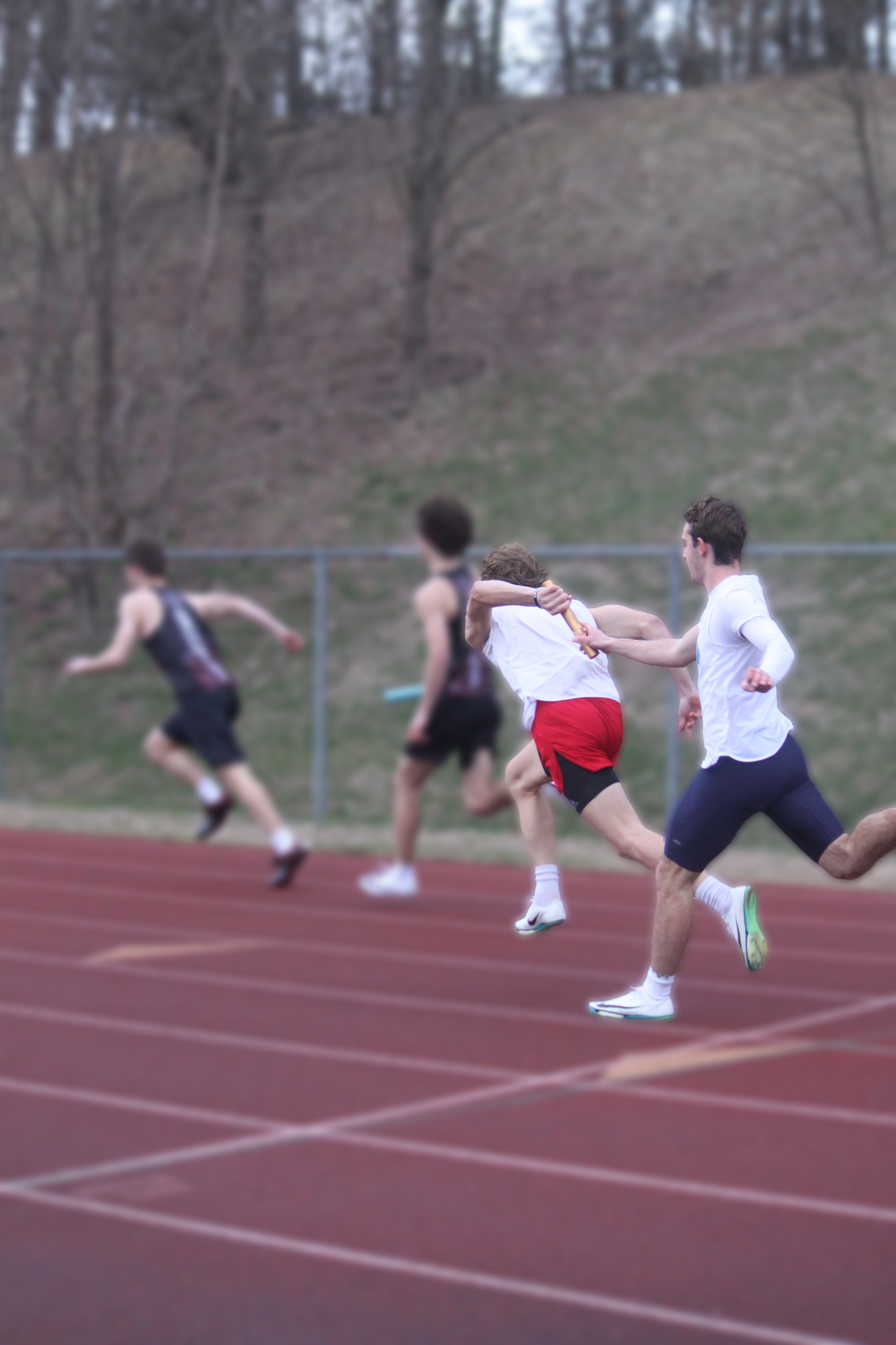 Senior Jon Inglese passes relay baton to senior Luc Gaudet at an away meet.