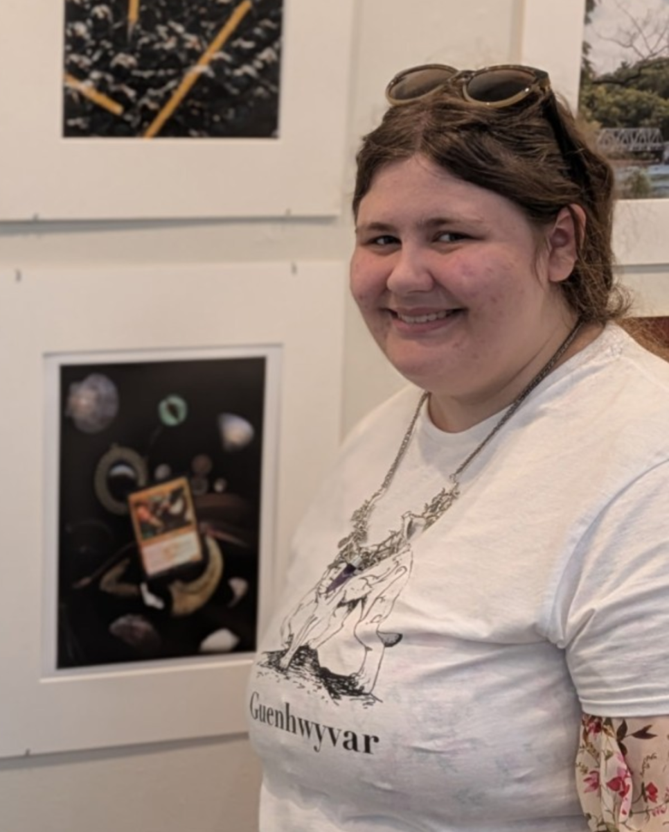 Senior Caitlyn Muller beside her art at a gallery at New England College. Muller is also pictured wearing a shirt with her own artwork.

Photo provided by Caitlyn Muller