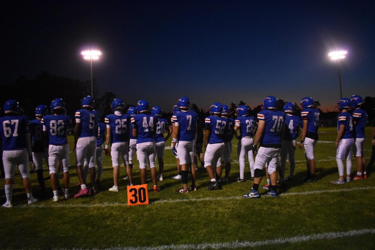 Under the Friday night lights, the Varsity Football Team stands united and ready to bring home the win.