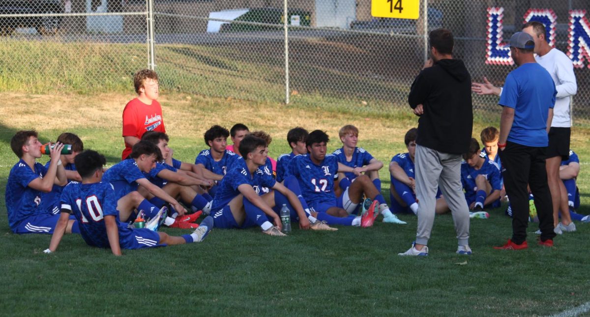 The team gathers on the field, listening closely to their coaches. 