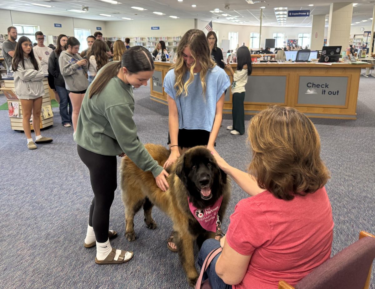 Students wait in line to pet Sophie, the pet therapy dog who visited LHS on Sept. 12. After becoming an official pet therapy dog through Pet Partners a year ago, Sophie and her handler, Wendy Calnan, have been visiting schools and universities to help students.