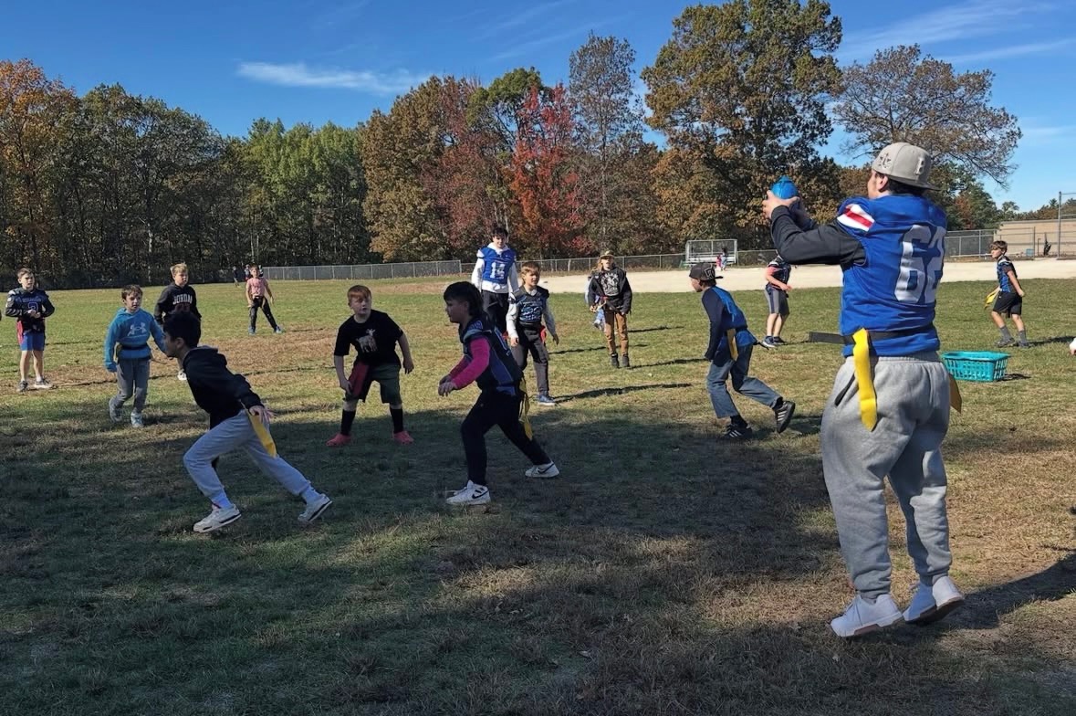 Athletic Leader Council member Matt Wolf engages with a group of Matthew Thornton elementary school students in a football game on the field next to the playground. 
Photos used with permission from Amy Downing.