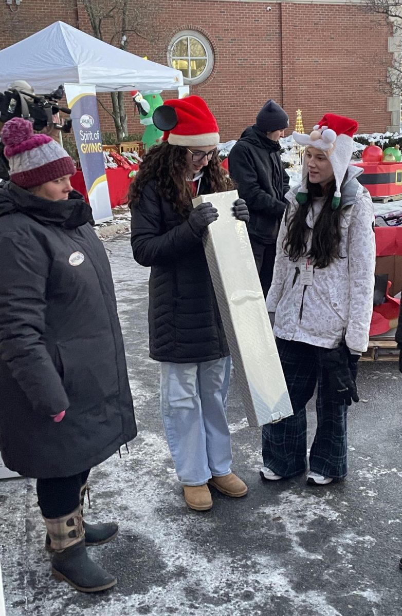 Seniors Emily Hoyt and Cassie St. Hilaire connect with WMUR employees as they help separate the unwrapped gifts and additional donations. Community Service Club members start preparing a month in advance for this event. (Photo used with permission from Susan Wakelin.)
