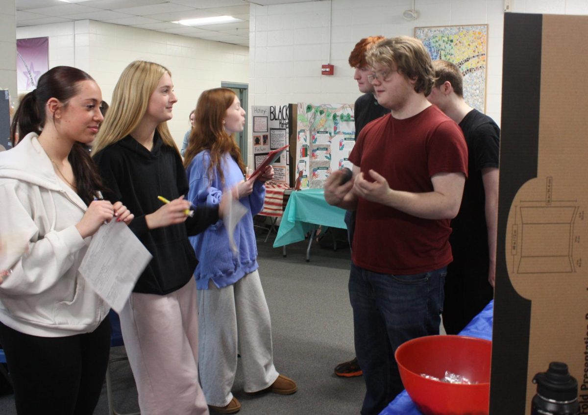Sophomores Laila D'Anna and Kaelyn Wheeler listen to junior Kai Spaulding's presentation on Haiti mythology.