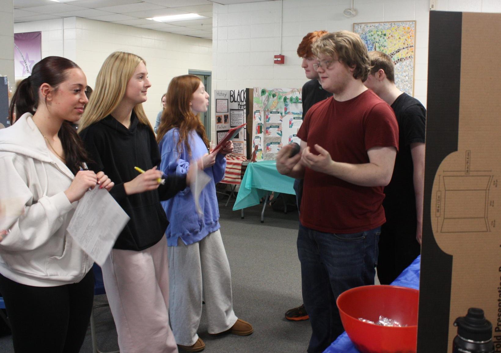 Sophomores Laila D'Anna and Kaelyn Wheeler listen to junior Kai Spaulding's presentation on Haiti mythology.
