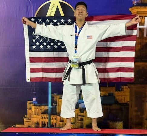 Sophomore Charlie Melia displays a U.S. flag out behind him on the second-place podium at the Malta Open International Karate Championships. He competed in Malta alongside his teammates from House of Samurai, who also trained and traveled with him for the event. “International championships make you try to focus more and train your best before competing,” he said. (Photo used with permission from Becky Taggart Melia).
