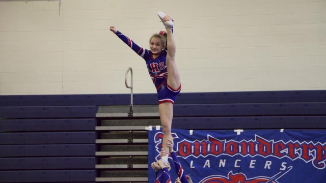 Freshman Emily Oulette strikes a pose in her stunt group as she is held up by her fellow cheerleaders. Photo by Sean O'Mara
