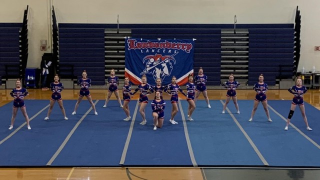 Varsity Cheerleading Team keeps the audience in anticipation, as they stand in formation waiting to begin their performance. Photo by Spencer McIntyre