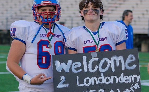 Michael Sampson and Jason Sensus hold up a sign that Winnacunnet fans made.