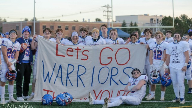 The team gathers around a Winnacunnet sign that the fans used throughout the game.