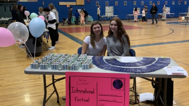 Juniors Amanda Fawcett and Rowyn Ferraro greet festival goers at the entrance and hand them look-alike U.S. Passports to document their stops at different countries' setups.